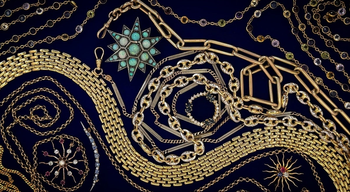 An assortment of gold-toned chains and jewelry pieces, including necklaces, bracelets, and a starburst pendant with turquoise stones, arranged in a spiral pattern against a dark navy blue background.